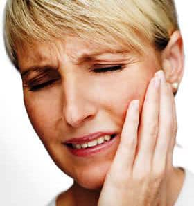 a woman holding her jaw from TMJ pain