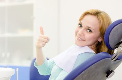 blonde woman giving a thumbs up in a dental chair