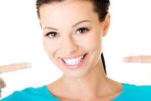An image of a woman happily pointing at her smile